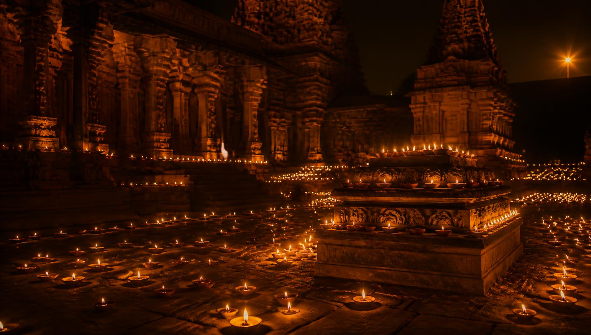 Courtyard of an Indian temple filled with lit clay diyas at night